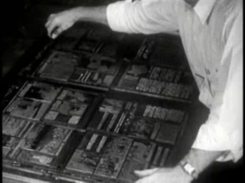Man arranging metal printing plates in a composing room flatbed chase, print shop
