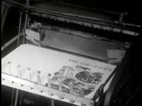Close-up of printed pages moving along a mechanical press conveyor.