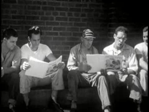 Group of workers reading printed magazines on benches outdoors, mid-century.