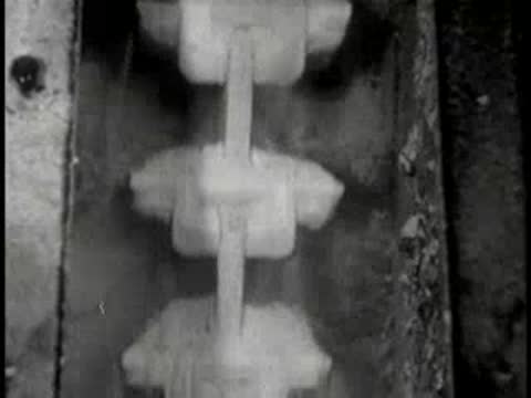 Industrial apparatus pouring a substance into molds, mid-century factory.