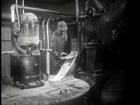 Worker operating industrial equipment in a factory setting, mid-century.
