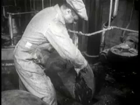 Worker handling heavy sacks in an industrial factory setting, mid-century.