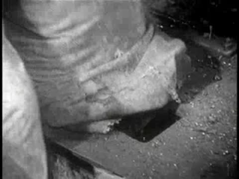 Close-up of a worker emptying a heavy sack into an industrial hopper.