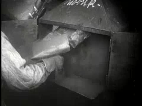 Worker handles paperwork or material at an industrial machine, black-and-white factory.