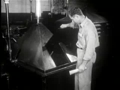 Worker at an industrial machine opens a hopper compartment in a factory.