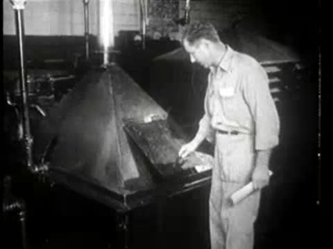 Worker closes the hopper on an industrial machine in a factory.