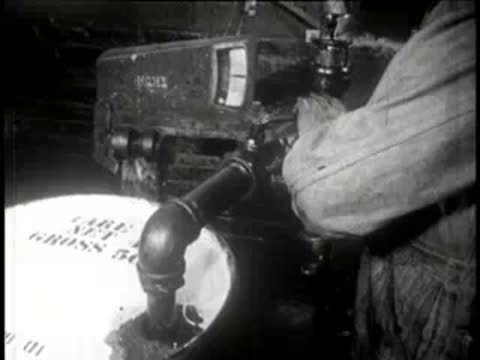 Close-up of a worker filling a barrel via a curved pipe.