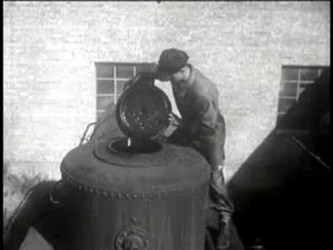 Worker climbs atop a large industrial tank to open its hatch.