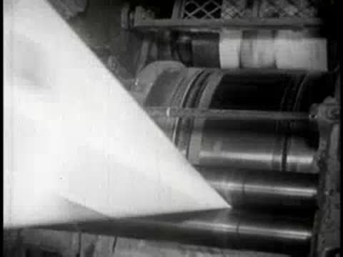 Industrial machinery guides paper sheets through high-speed printing rollers.