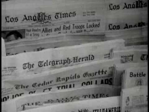 Newspapers being handled and stacked in a bustling newsstand area.