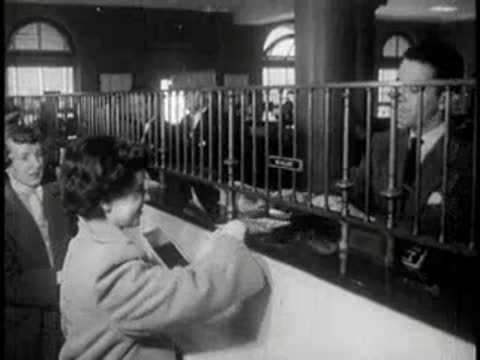 Customers and bank tellers interact across a vintage teller window counter.