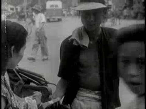 Street vendor in a wide-brimmed hat interacts with a customer outdoors.