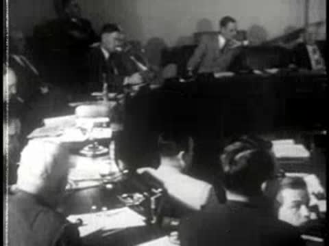 People seated around a long conference table during a formal meeting.