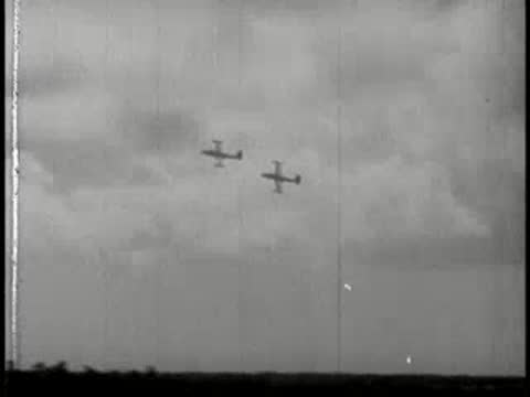 Two airplanes flying in formation through a cloudy sky.