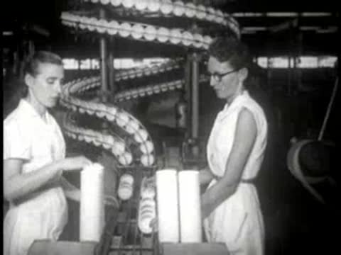 Female factory workers inspecting and packaging paper cups on a production line.