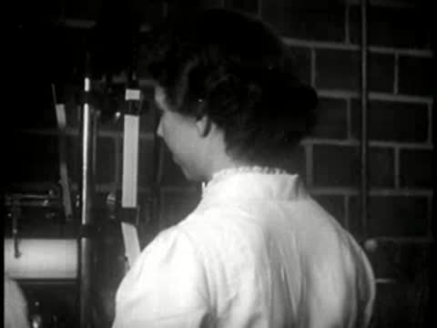 A female factory worker inspecting paper products near machinery.