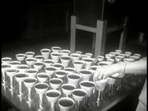 Workers testing and quality checking paper cups arranged on a table.