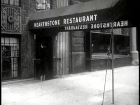 A woman walking past the entrance of the Hearthstone Restaurant.