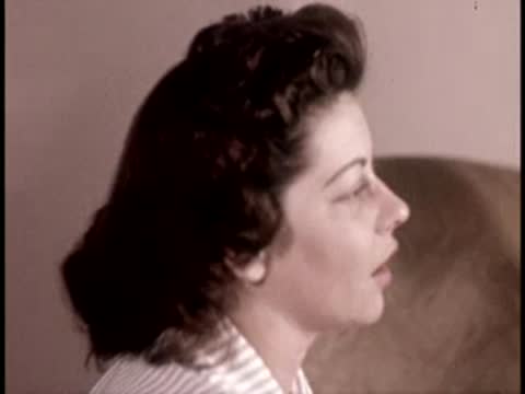 Profile view of a woman sitting indoors, 1950s hairstyle and fashion