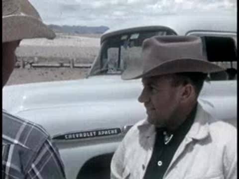 A person talking near a white Chevrolet Apache truck parked in an open landscape