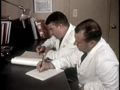 Two people sitting at a desk reviewing and signing documents in an office setting