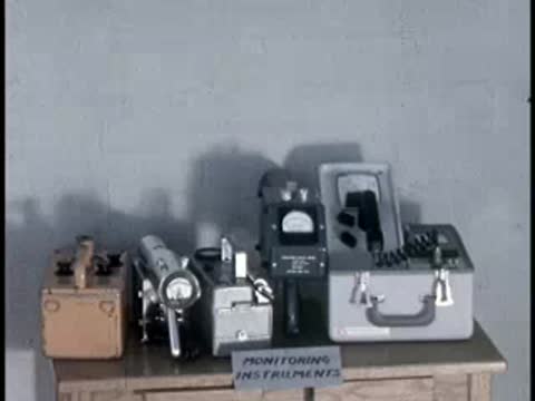 Various monitoring instruments and Geiger counters displayed on a table surface