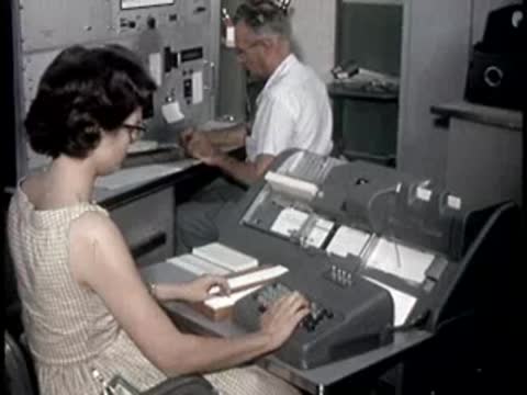 A person operating specialized data processing equipment in an office or control room
