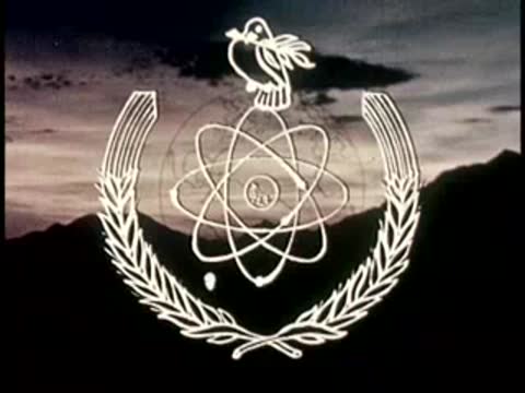 Animated graphic of atom symbol with wreath against sunset sky.