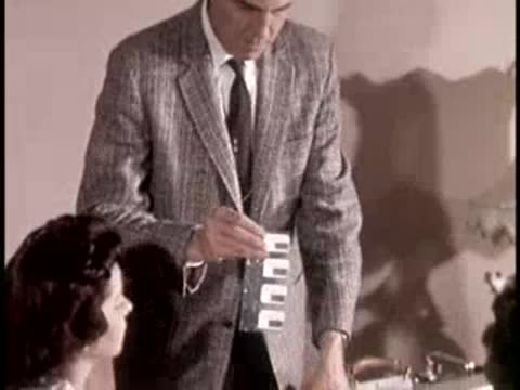 A man holds up a strip of film badges and distributes them indoors