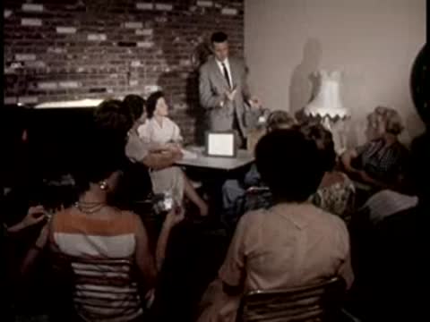 A man gives a presentation to an audience of women seated indoors