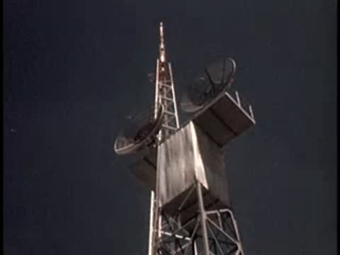 Exterior shot of a tall radio tower with satellite dishes, clear sky