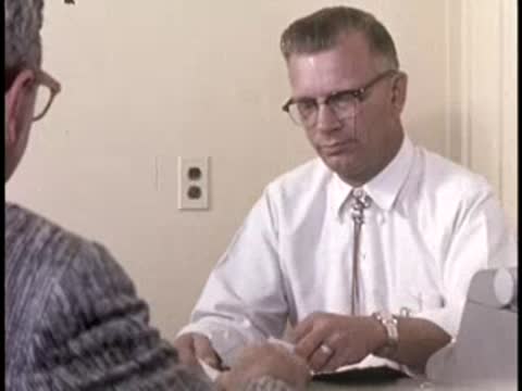 Two men seated at a desk reviewing papers, retro office setting