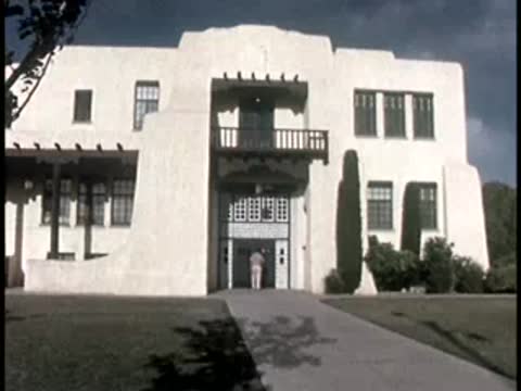 exterior view of a large white building with arched entryway under cloudy sky