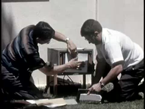 two men kneeling and removing paper chart from a scientific instrument case