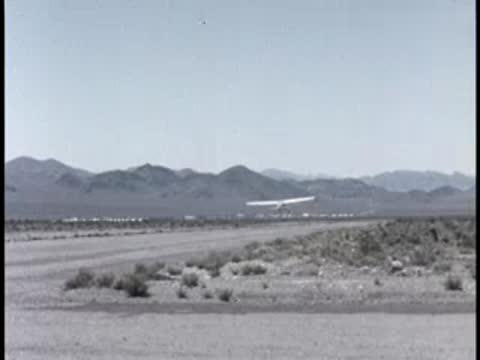 small airplane taking off from a dirt runway with mountains in distance