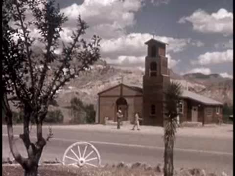 historic church building with wagon wheel and desert landscape in the background