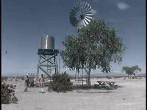 windmill, water tower, tree, and picnic table at an outdoor desert site