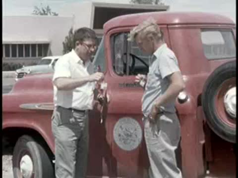 two men shaking hands near red pickup truck outdoors