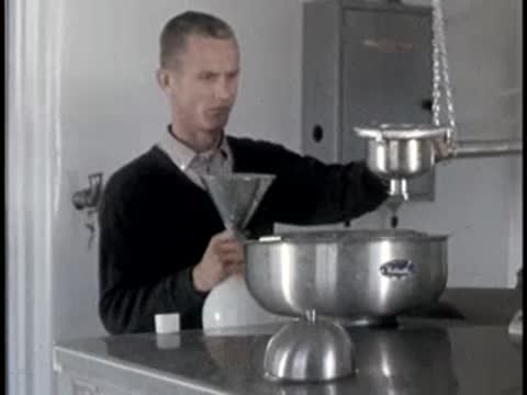 man using funnel and bottle setup in laboratory or kitchen