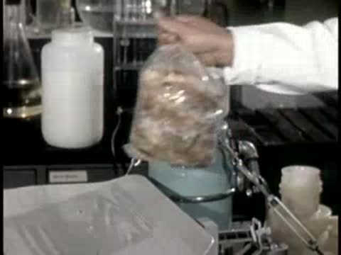 man handling bag of sample material near laboratory equipment