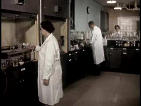 laboratory interior with workers in white coats moving around