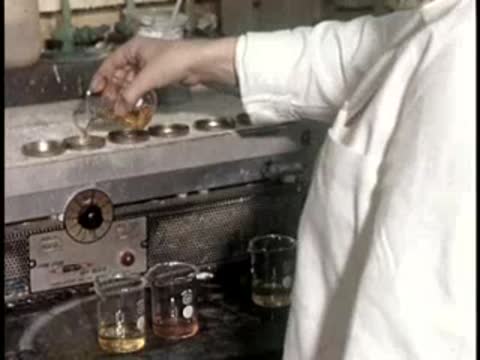 worker pouring liquid samples into small glass containers on hotplate