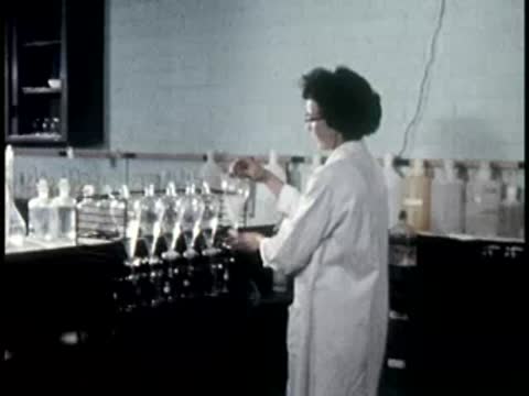 worker in white coat standing near laboratory glassware setup