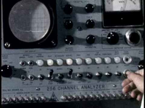 A close-up of hands adjusting dials and switches on a complex electronic console.