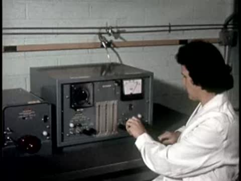 A lab technician in a white coat adjusts settings on a laboratory instrument.