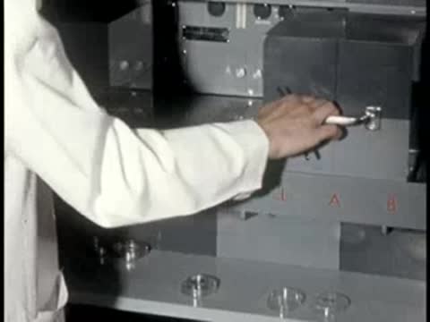 A lab technician opens a metal drawer in a piece of modular laboratory equipment.