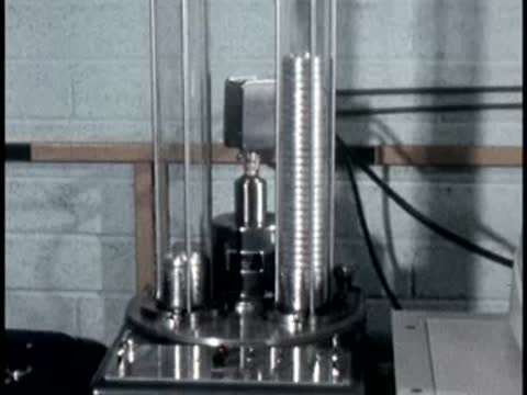 A close-up view of a metal stack inside a tall vertical glass laboratory tube.