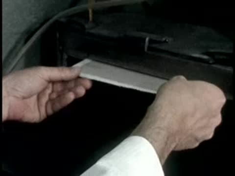 Hands remove a printed paper chart from a mechanical laboratory printer.