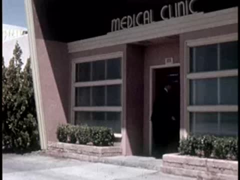 Exterior shot of a modern medical clinic building with large glass windows and plants.