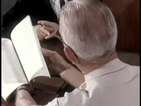 A person turning pages of an instructional booklet containing photographs and charts